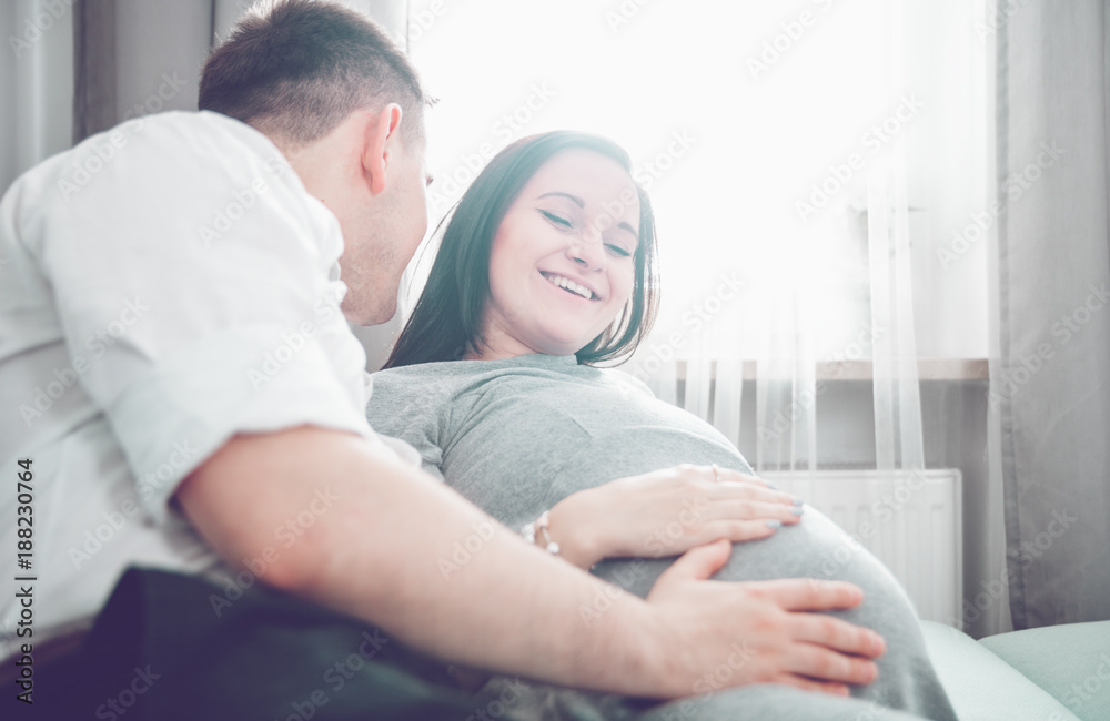 Cheerful pregnant couple relaxing at home and enjoying pregnancy time Cheerful pregnant couple relaxing at home and enjoying pregnancy time