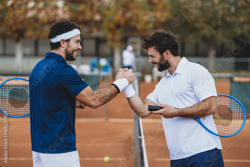 Two young men handshake after a tennis match on a clay court