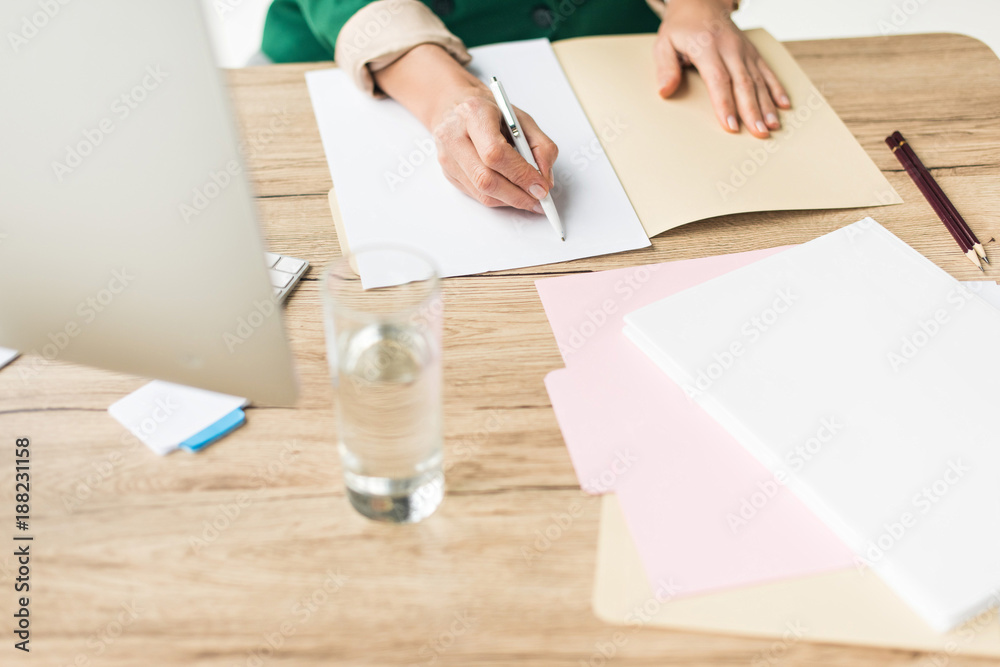 partial view of businesswoman doing paperwork at workplace
