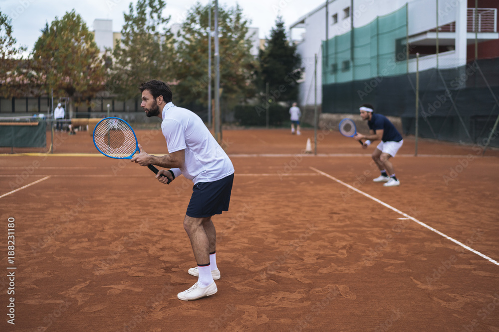 Group of friends play tennis a double match on a clay court Group of friends play tennis a double match on a clay court