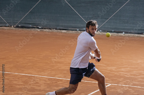 Young man playing tennis on a clay court