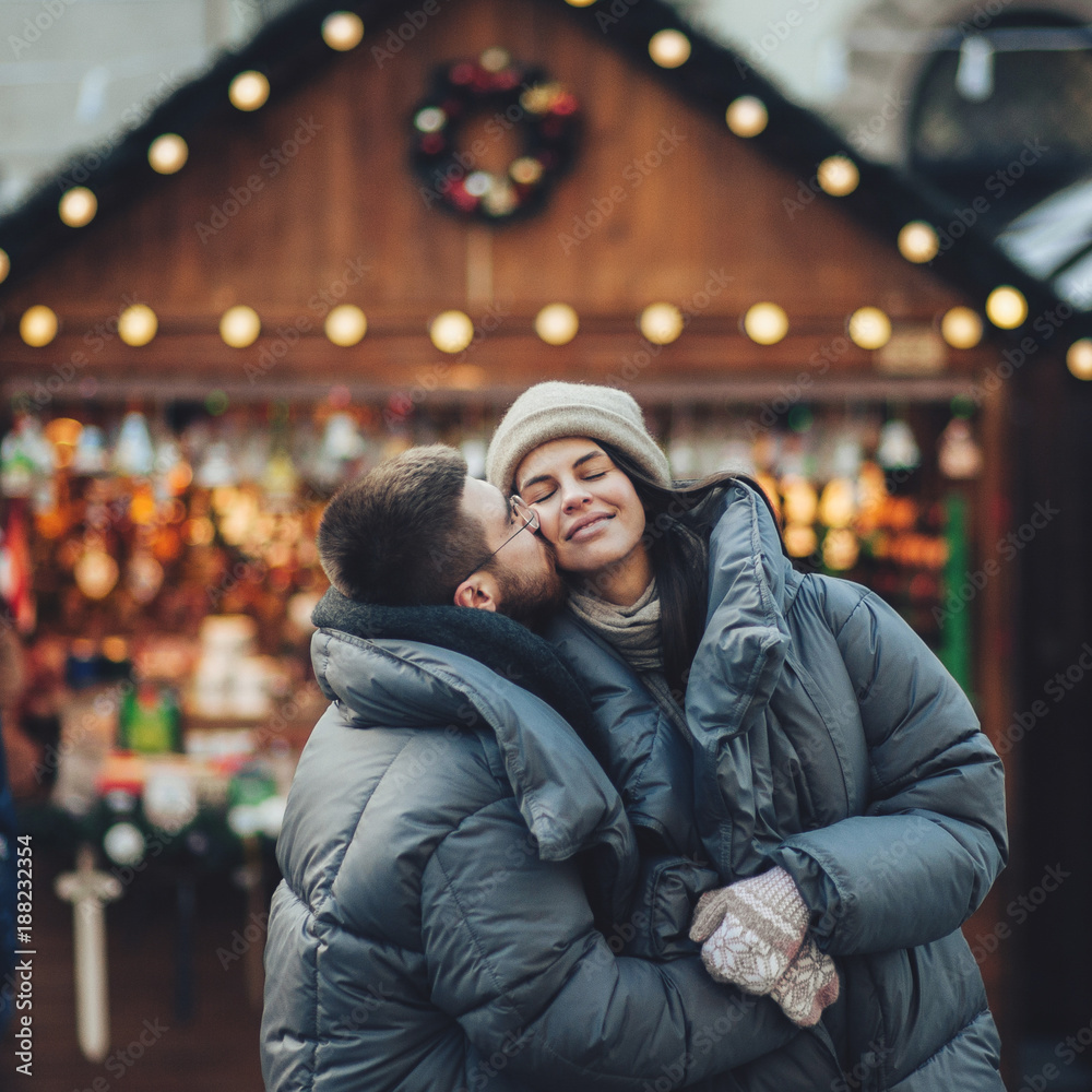Fototapeta premium Happy couples on the city square decorated for a Christmas marke 
