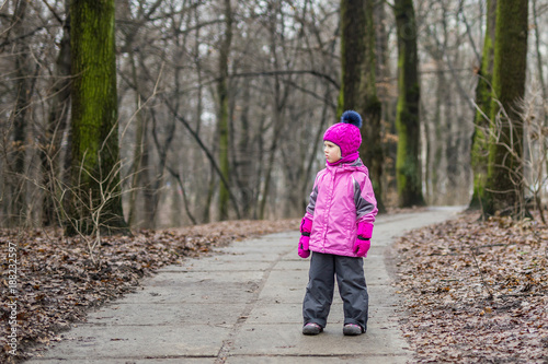 Little girl walking alone in a forest at autumn