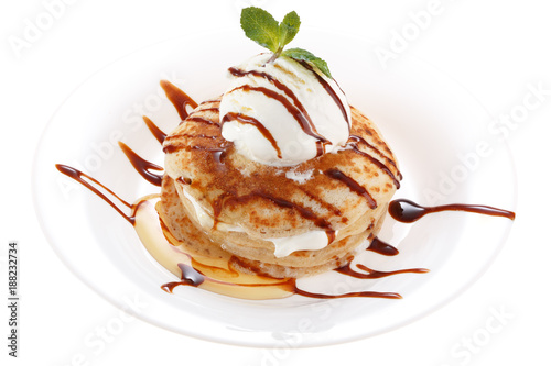 Serving pancakes with ice cream on the plate. Decorated with chocolate syrup and mint. Isolated on white background.