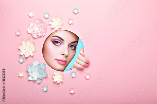 Conceptual Beauty Portrait of Beautiful Young Woman. Face of Girl with Spring Pink Make-up. Beauty Fashion Model Woman Face perfect Skin. Paper Flowers on Pink Background