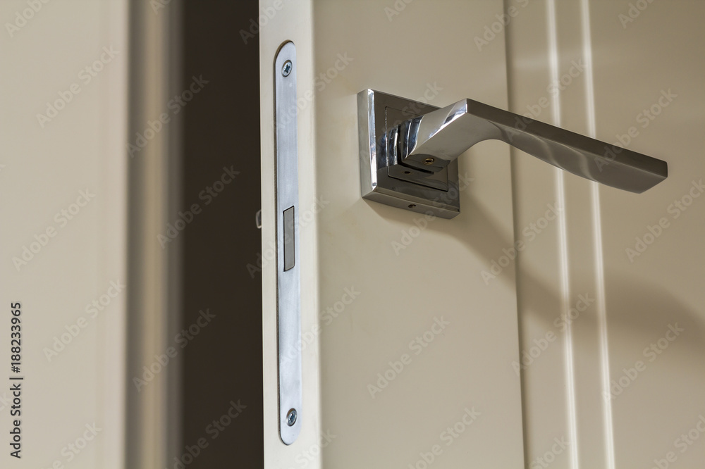 Naklejka premium Modern stainless steel door handle on white wooden doors