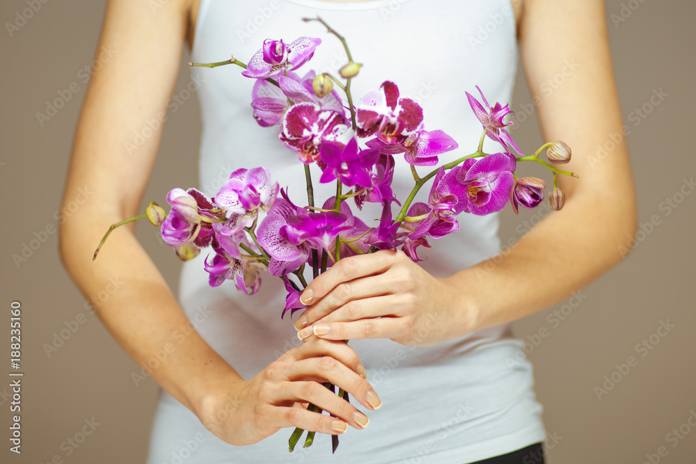 woman hands holding some violet orchid flowers, sensual studio shot