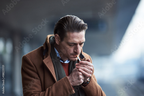 Portrait of serene man lighting up cigarette while locating in street.  Tobacco concept Stock Photo | Adobe Stock