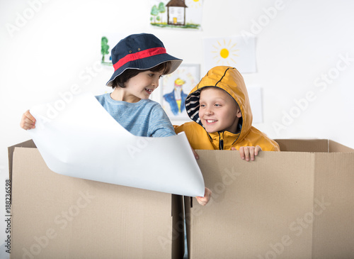 Foto Cheerful kids playing marine adventure games, boys are standing inside of carton