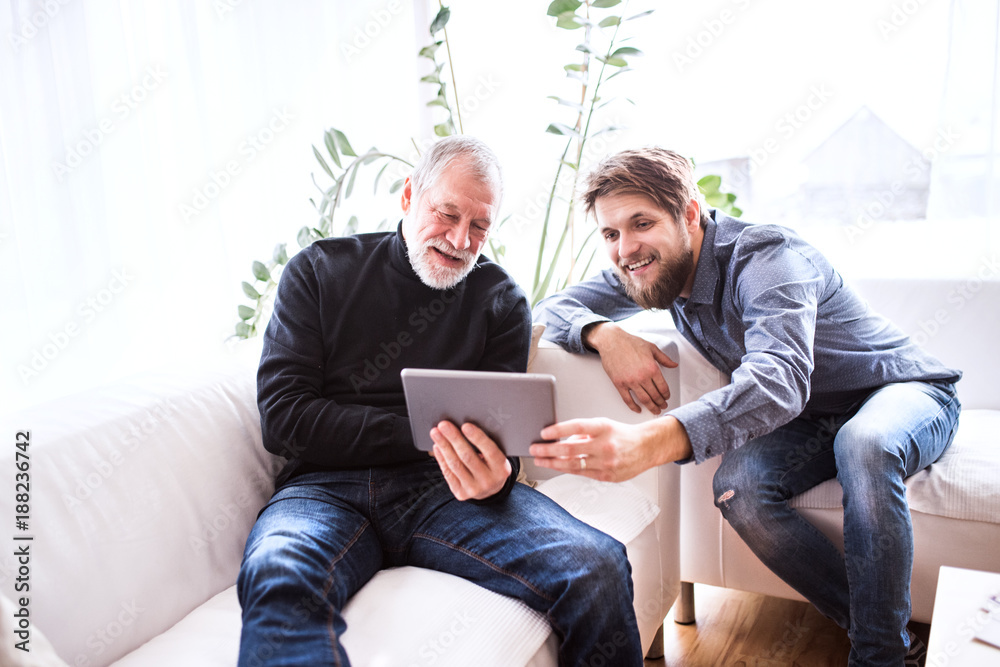 Hipster son and his senior father with tablet at home.
