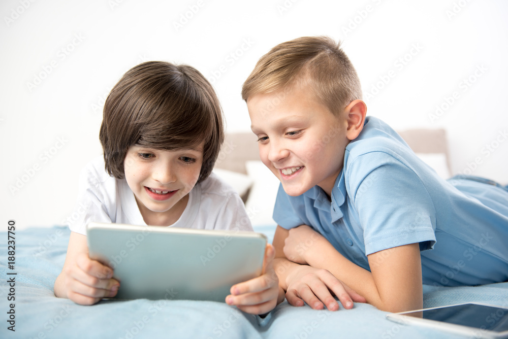 Laughing friends staying indoors and watching funny video on the tablet Laughing friends staying indoors and watching funny video on the tablet