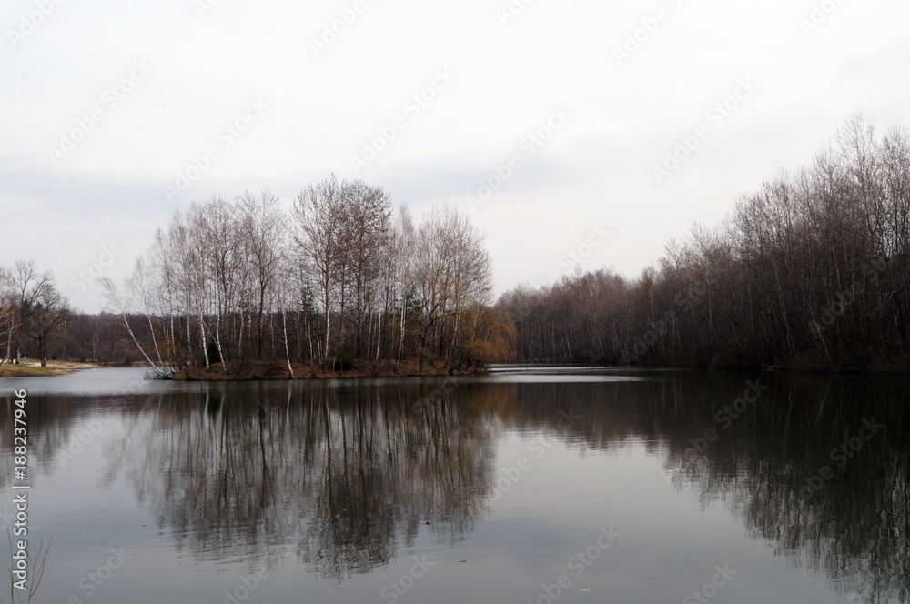 View of the lake near the autumn forest with a small island in the middle