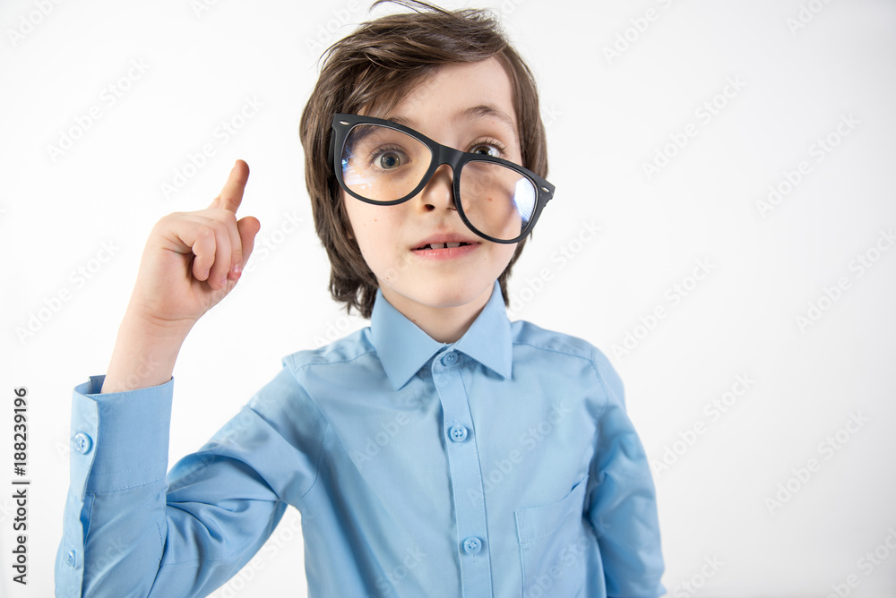 That is it. Portrait of uncombed kid with glasses aslant dreaming of making scientific breakthrough. He is holding finger up. Isolated on background That is it. Portrait of uncombed kid with glasses aslant dreaming of making scientific breakthrough. He is holding finger up. Isolated on background