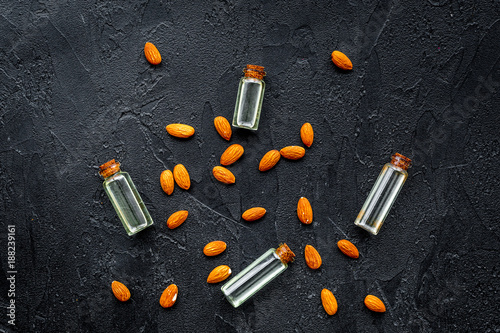 Oil for skin care. Almond oil in glass bottles on black background top view