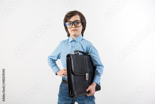 Waist up portrait of serious boy with portfolio trying on the role of an office worker. Isolated on background