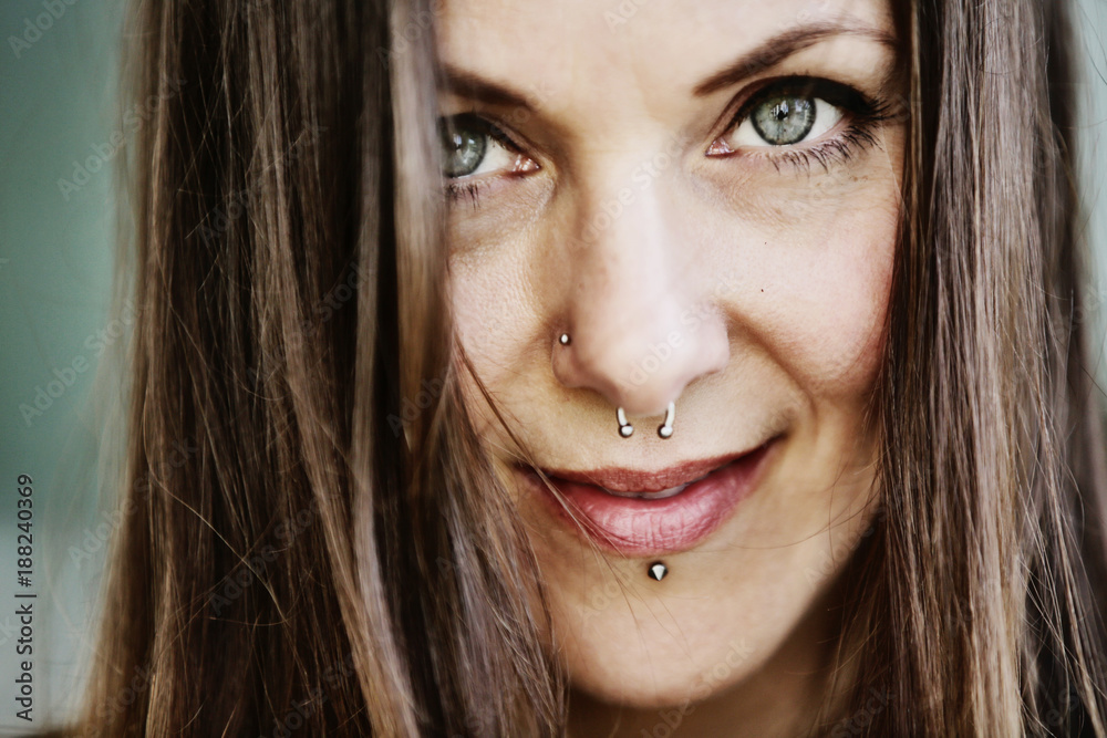 junge Frau, langhaarig, mit Piercings im Gesicht schaut verführerisch in die Kamera StockFoto