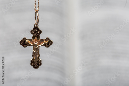 Golden Cross on background of the open Bible