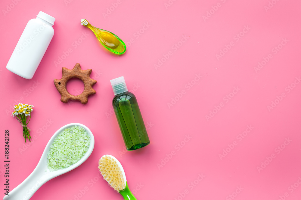 Children's means hygiene with chamomile. Bottles, spa salt, tooth brush and toy on pink background top view copy space Children's means hygiene with chamomile. Bottles, spa salt, tooth brush and toy on pink background top view copy space