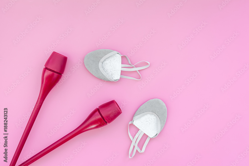 Equipment for rhythmic gymnastics. Clubs and gymnastics shoes on pink background top view on pink background top view copy space Equipment for rhythmic gymnastics. Clubs and gymnastics shoes on pink background top view on pink background top view copy space