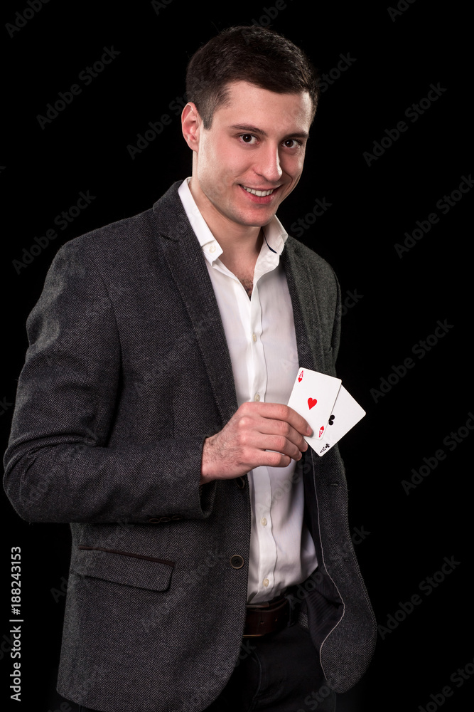 Young caucasian man wearing suit holding two aces in his hand on black background. Gambling concept. Casino Young caucasian man wearing suit holding two aces in his hand on black background. Gambling concept. Casino