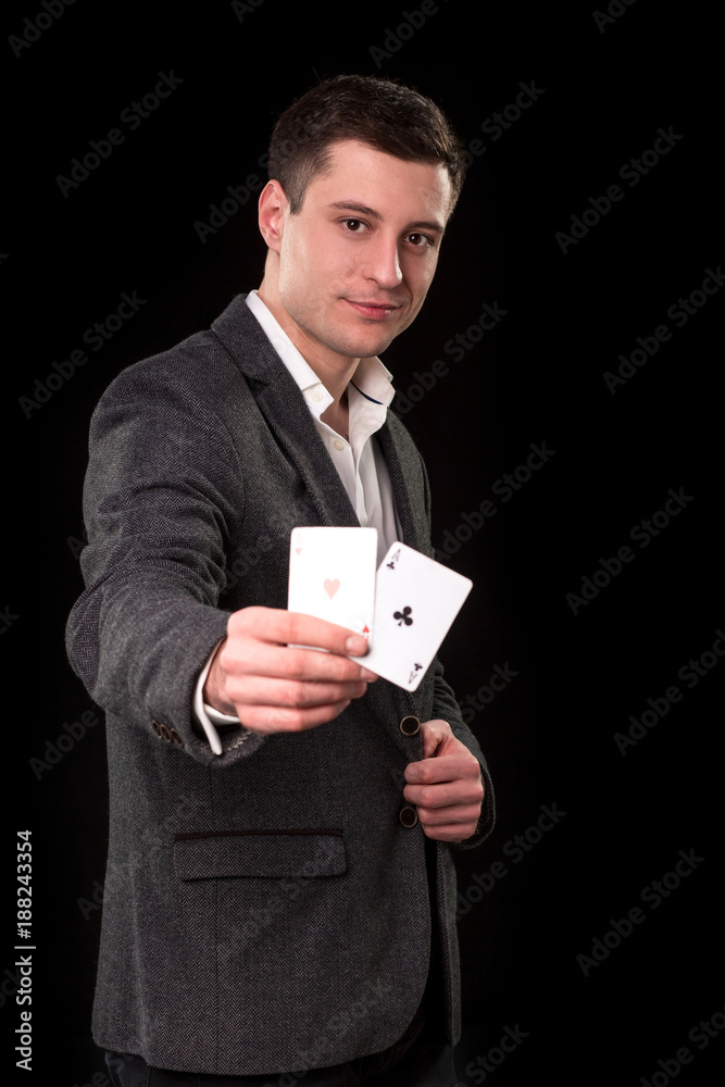 Young caucasian man wearing suit holding two aces in his hand on black background. Gambling concept. Casino Young caucasian man wearing suit holding two aces in his hand on black background. Gambling concept. Casino