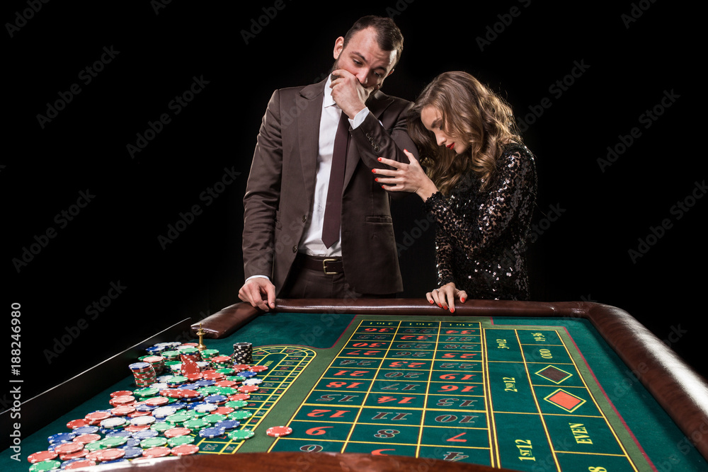 Man and woman playing at roulette table in casino Man and woman playing at roulette table in casino