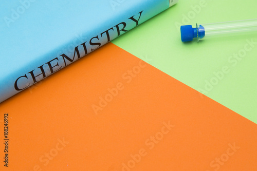 Education concept: Chemistry student's book and empty test tube on a bright orange and green background with copy space