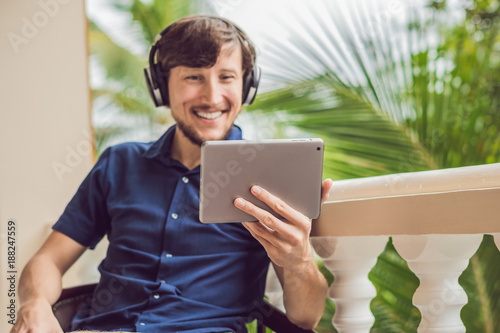 man in tropics talking with friends and family on video call using a tablet and wireless headphones photo