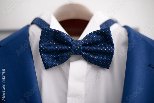 Close-up elegant blue suit with white shirt and blue bow tie, in preparation for a formal event, job interview or a wedding ceremony, or as part of office attire
