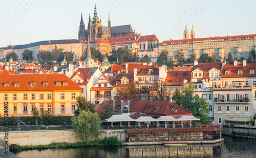 Orange tile roofs and castle behind from Charles Bridge at sunrise