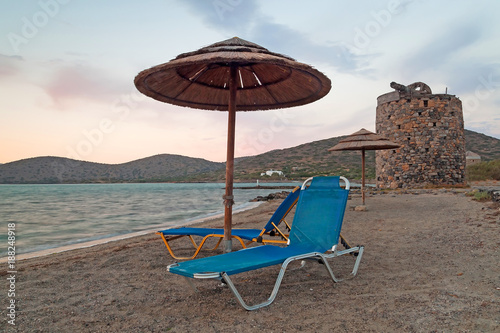 Beach with parasol at Mirabello Bay at sunset, Greece
