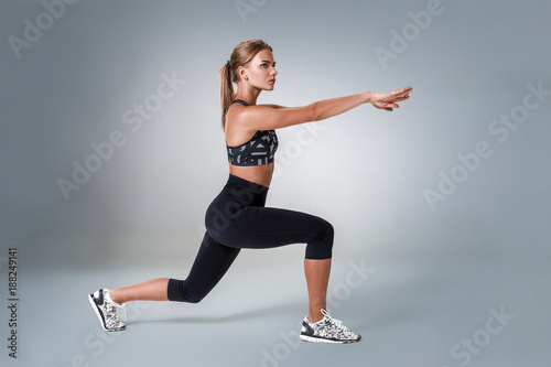 Stretching workout posture by a woman on studio gray background