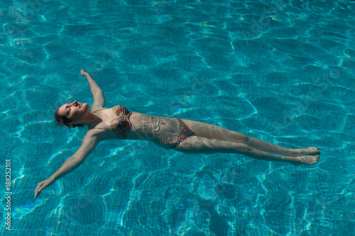 Young woman in swimsuit is swimming in pool
