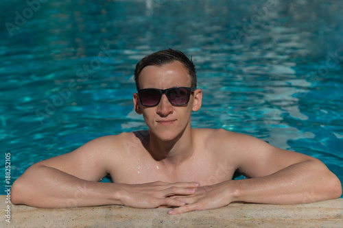 Man in sunglasses swimming in an outdoor pool
