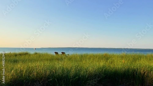 Green grass blowing in wind by the water and boat 