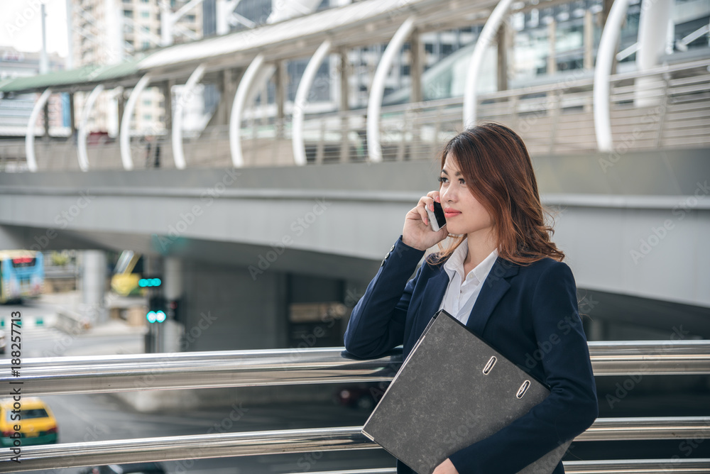 Fototapeta premium Portraits of beautiful asian woman look confidence is standing and holding cellphone . she using smartphone calling to conversation with customer.