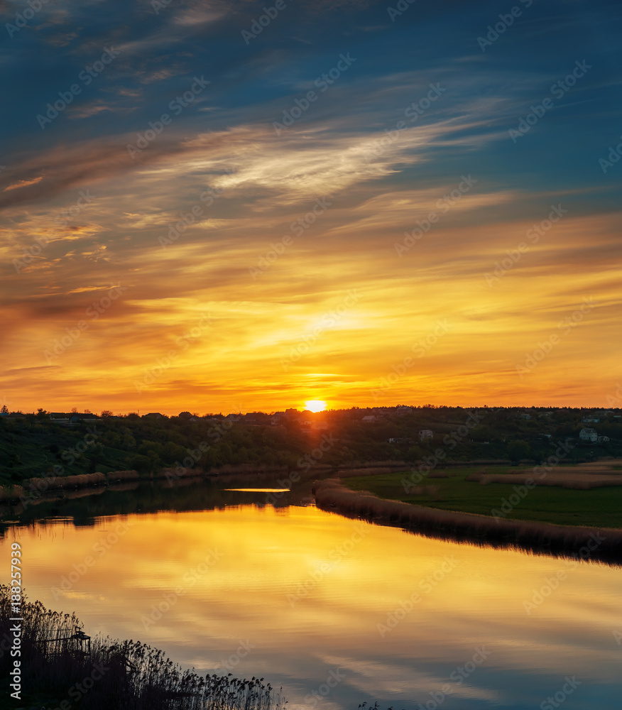 Fototapeta premium orange sunset in dramatic clouds over river