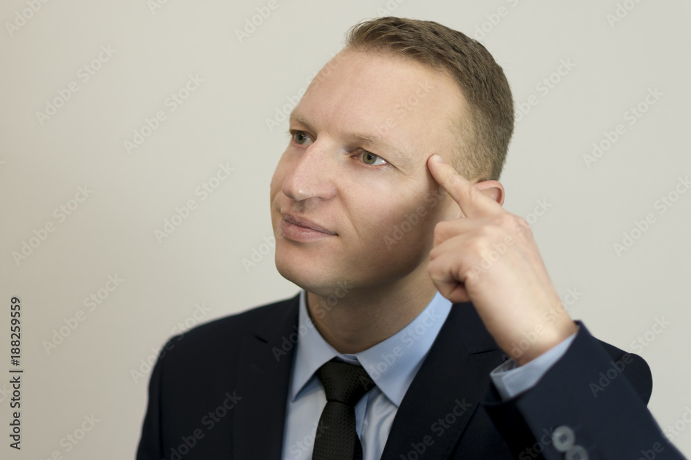 Closeup portrait of buisness man gesturing with his finger against his temple Closeup portrait of buisness man gesturing with his finger against his temple