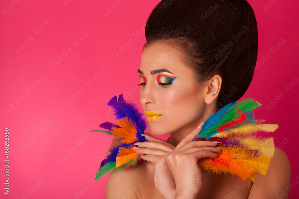 Fototapeta premium Pretty young woman on colorful background holding feathers. Portrait of attractive girl with creative make up