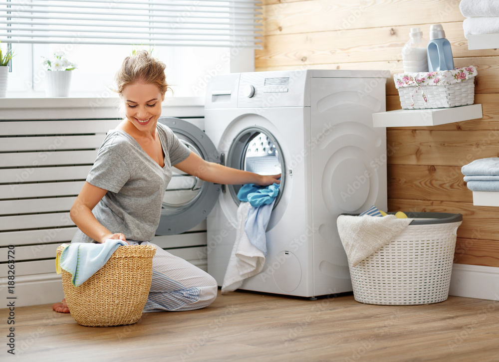Happy housewife woman in laundry room with washing machine - obrazy, fototapety, plakaty 