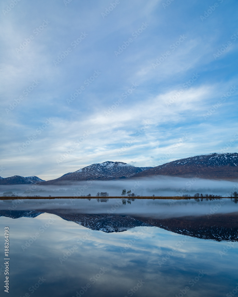 landscape view of scotland and loch tulla at blue hour in winter with calm waters and fog 