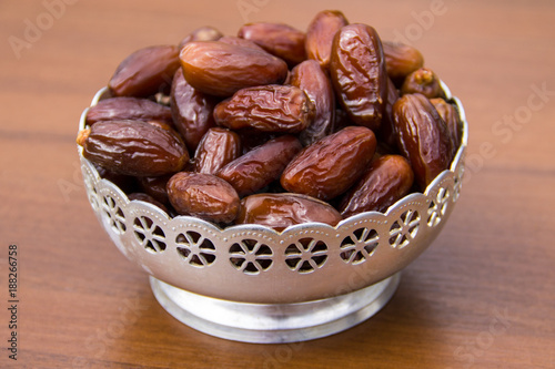 Dates fruit on a silver bowl on wooden table. The Muslim feast of the holy month of Ramadan Kareem
