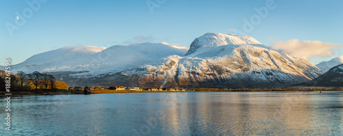 landscape view of scotland and ben nevis near fort william in winter with snow capped mountains and calm blue sky and water