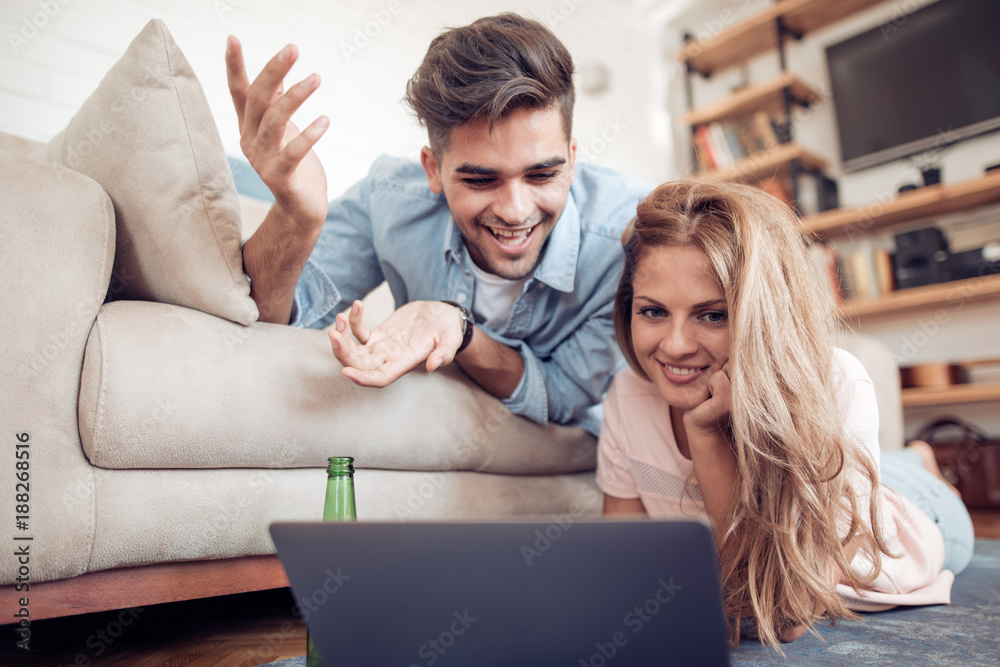 Fototapeta premium Beautiful young couple in casual clothes is using a laptop.