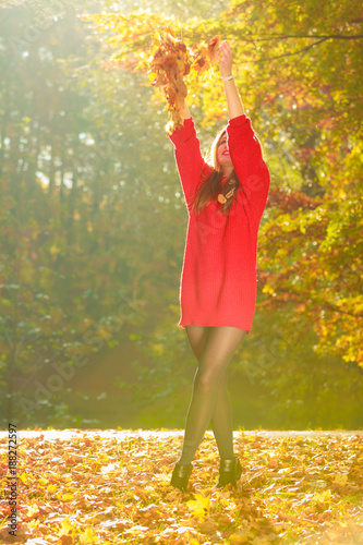 Joyful girl having fun with leaves in autumnal park.