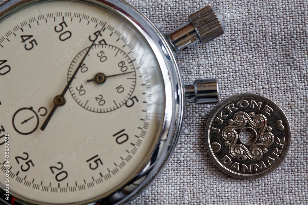 Denmark coin with a denomination of 1 krone (crown) and stopwatch on linen canvas backdrop - business background