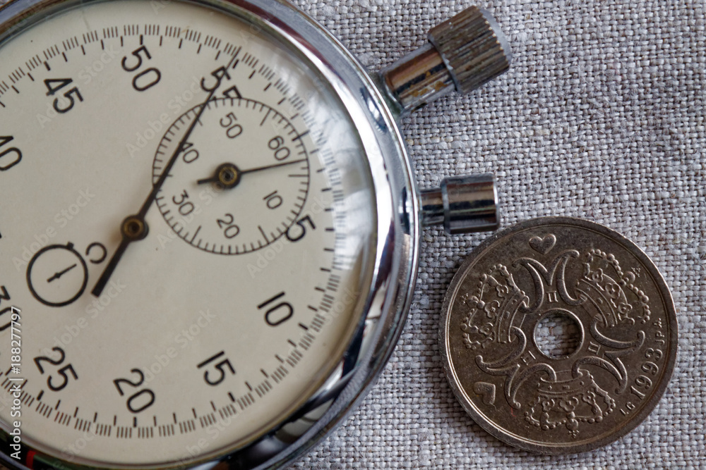 Denmark coin with a denomination of two crown (krone) (back side) and stopwatch on flax canvas backdrop - business background Denmark coin with a denomination of two crown (krone) (back side) and stopwatch on flax canvas backdrop - business background