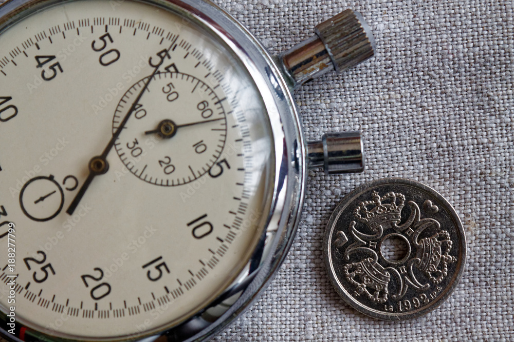 Denmark coin with a denomination of one crown (krone) (back side) and stopwatch on flax canvas backdrop - business background