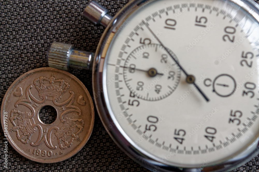 Denmark coin with a denomination of five crown (krone) (back side) and stopwatch on brown denim backdrop - business background