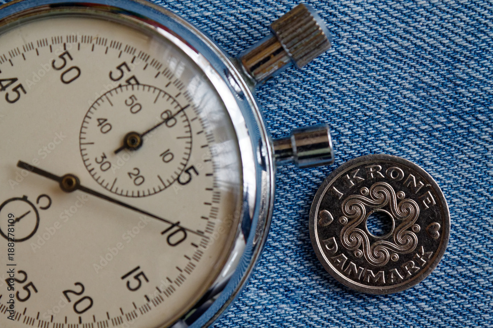 Denmark coin with a denomination of 1 krone (crown) and stopwatch on old blue jenas backdrop - business background